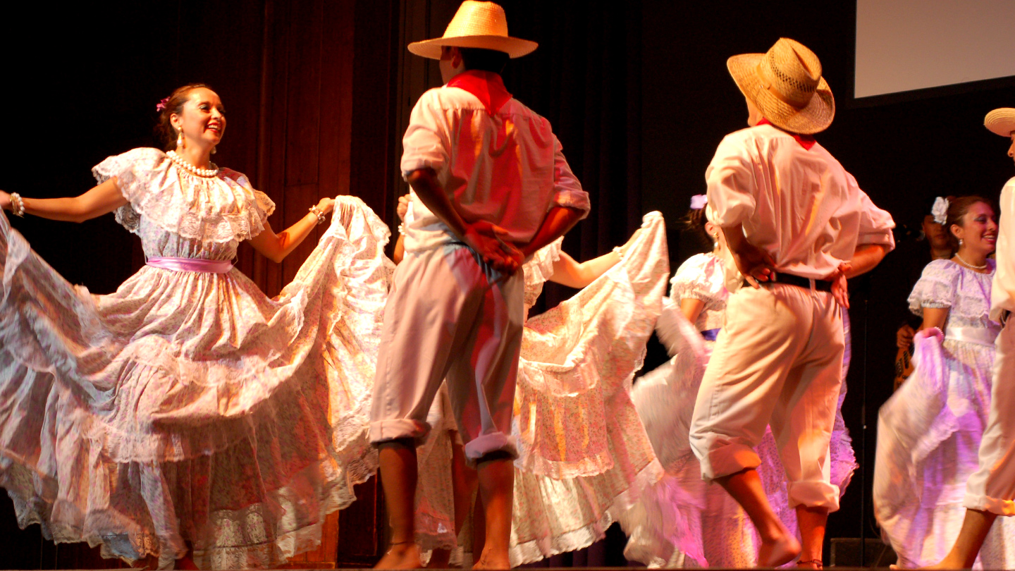 Three male/female dance pairs in costume dancing on stage.