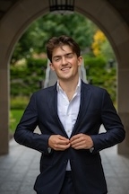 A man in a suit smiles at the camera.