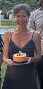 A woman smiling with a birthday cake.