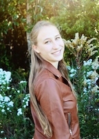A woman in a leather jacket smiles at the camera.