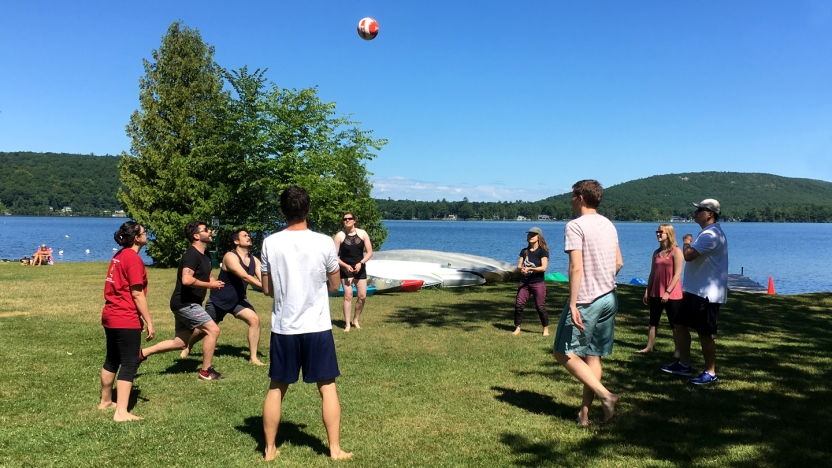 A group of Portuguese school students playing volleyball on a field next to a lake.
