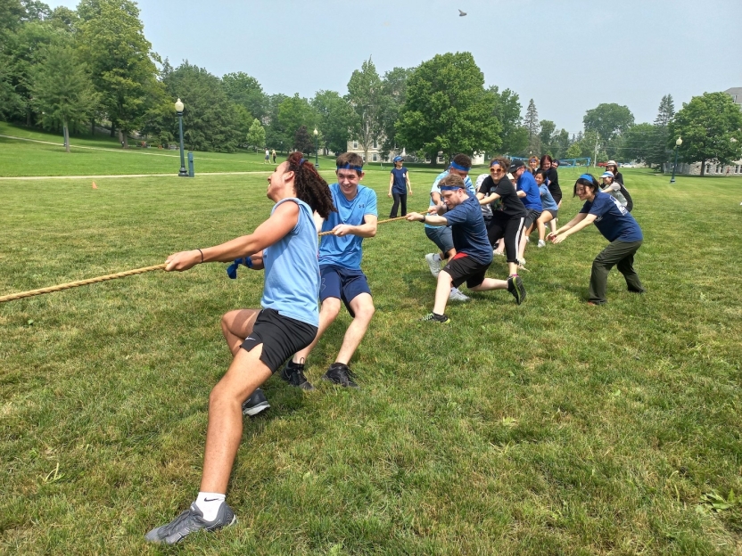 a group of students pulls a rope, all wearing blue. 