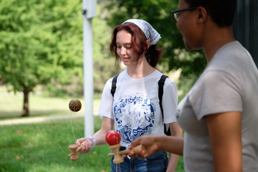 Students attempt to get a wooden ball to balance on a platform, smiling.