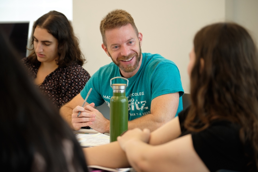 A student in a teal shirt smiles at his classmates.