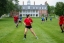 Students play soccer outside in red shirts.
