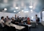 Students sit in a large, airy classroom.