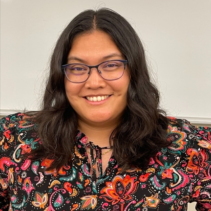 Photo of female librarian smiling, wearing glasses and a colorful shirt
