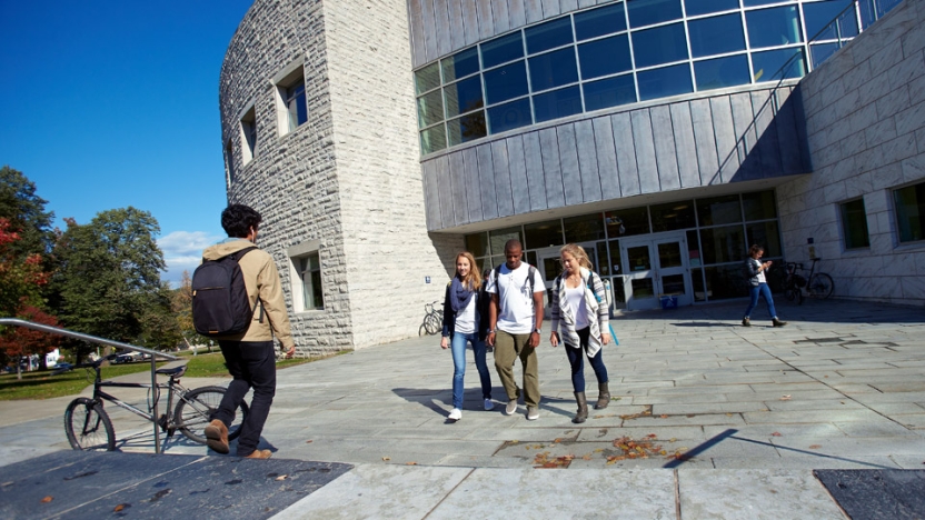 Students walking outside entrance to Davis Library on sunny day.