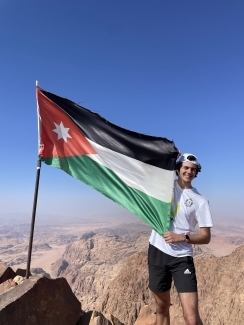 A student smiling and holding the Jordanian flag