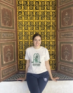Student smiling in front of intricate yellow tile