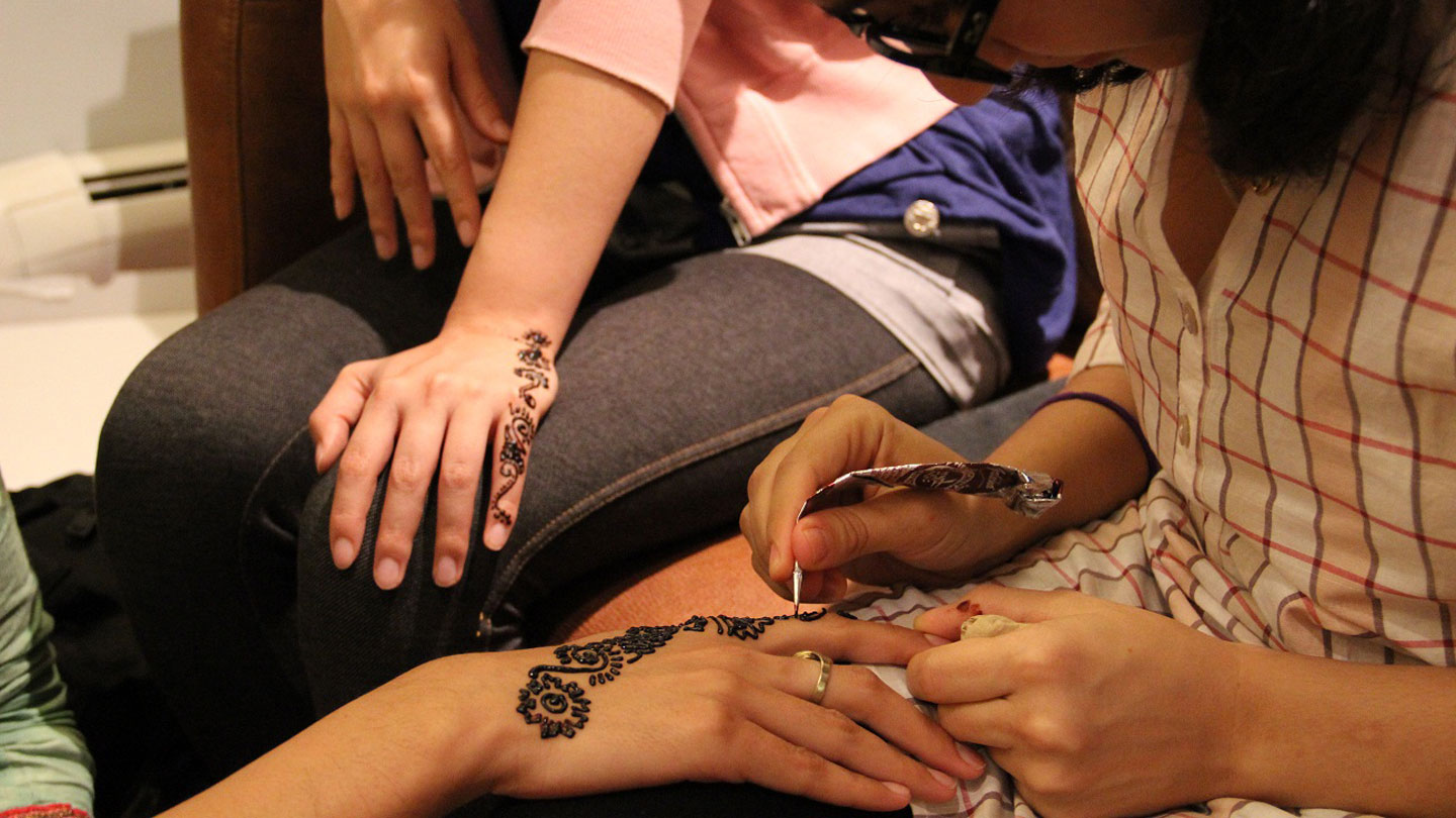 Students painting with henna on their hands.