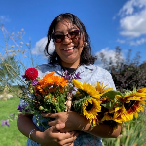 Knoll intern wearing sunglasses smiling and holding bouquet of flowers