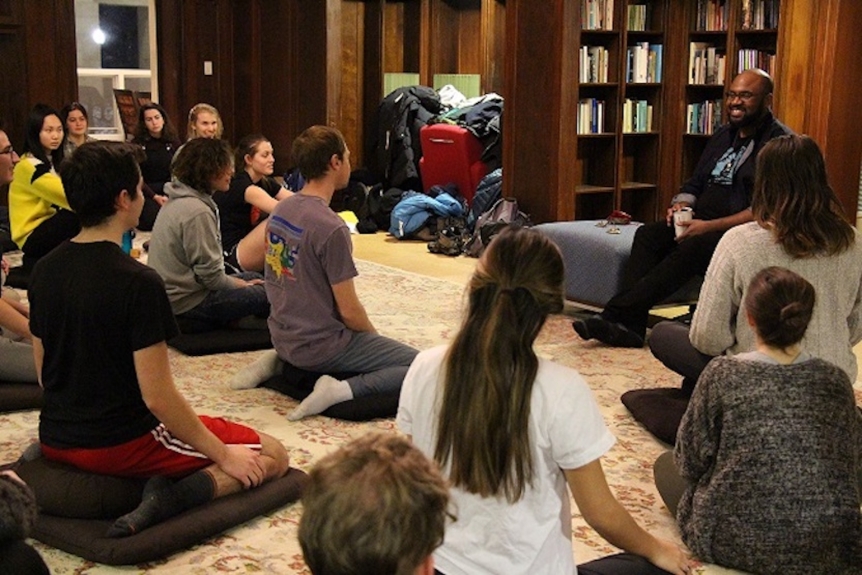 students sitting on meditation cushions listening to Lama Rod Owens lead them 
