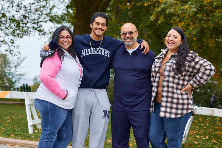 A family pose for a photo outside of proctor dining hall. 