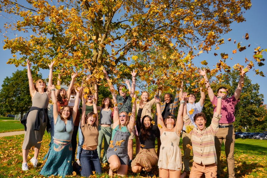 Students throw leaves in the air during Fall Family Weekend 2023