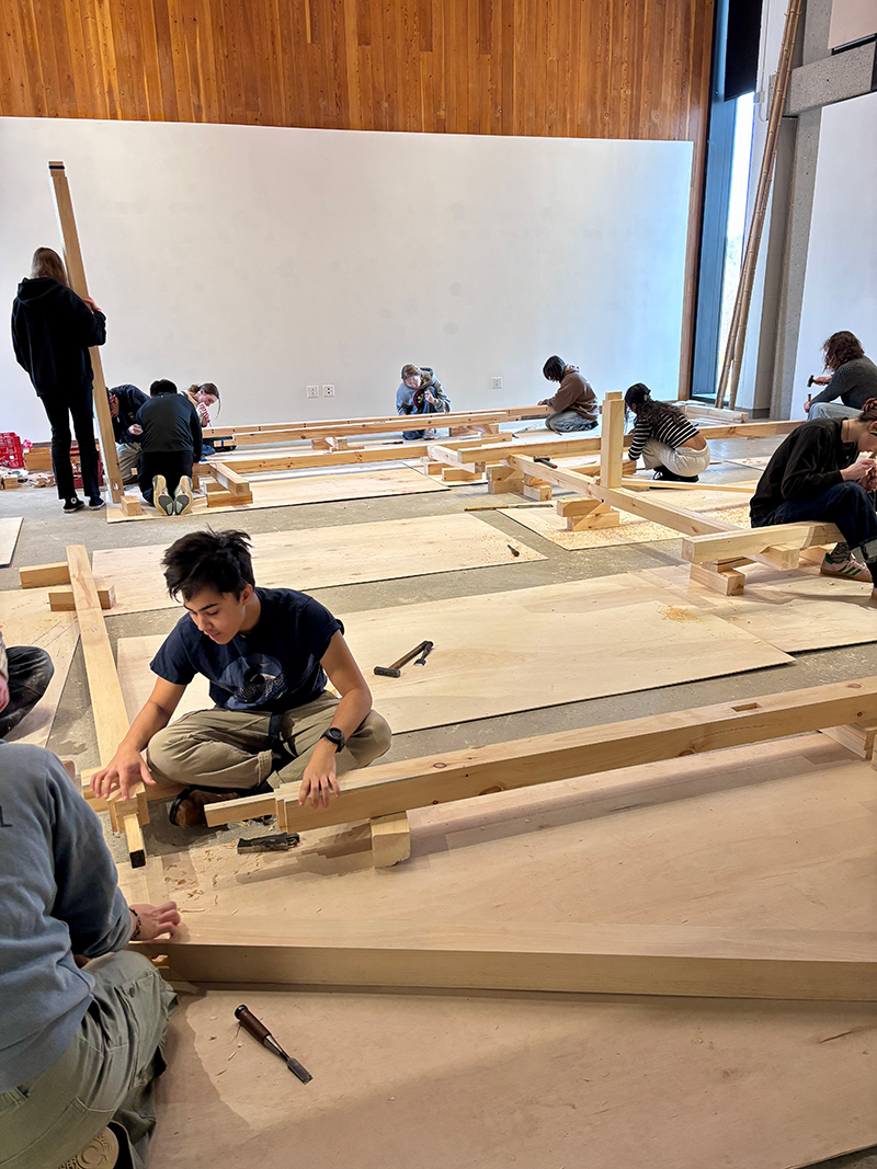 A student works on a timber with chisel and hammer