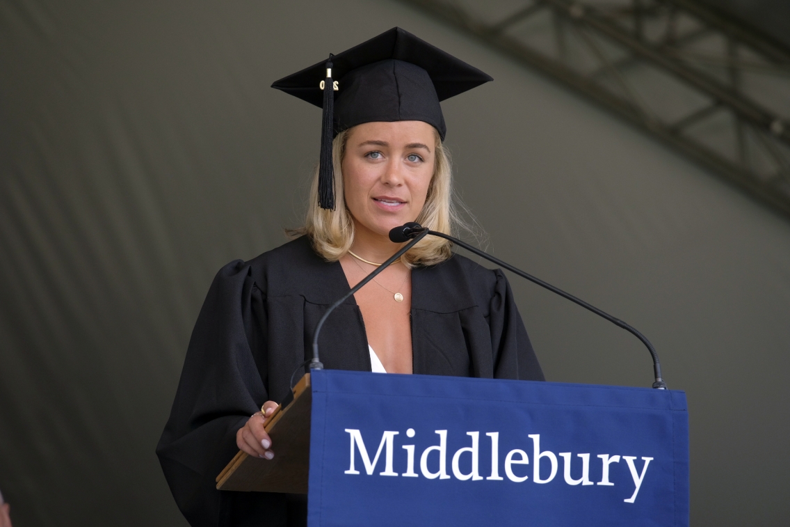 A student stands at the podium in cap and gown to give the student commencement address.