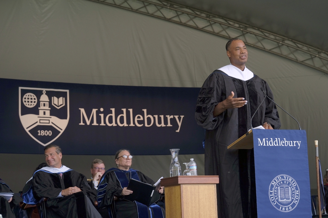 Commencement speaker standing at podium surrounded by the platform party.