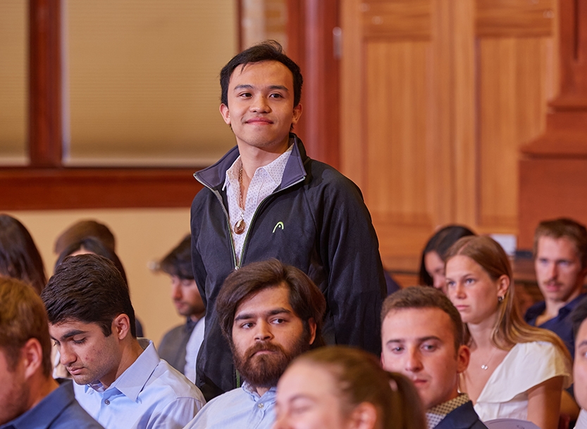 Student stands to be recognized among a group of seated students at an awards ceremony.