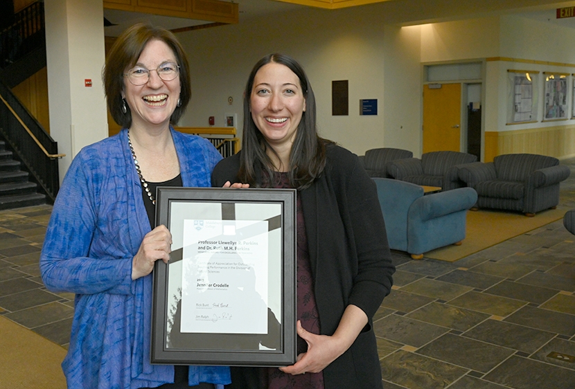 Susan Harris and Professor Jennifer Crodelle hold the Perkins Award and look toward camera.