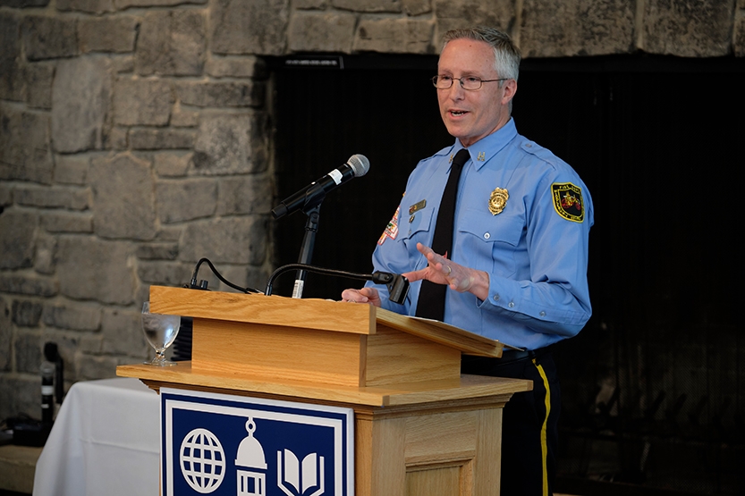 Man in firefighting uniform stands at lectern to deliver remarks.