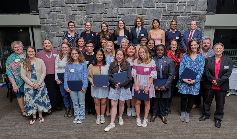 A group of students poses for a photo holding award certificates.