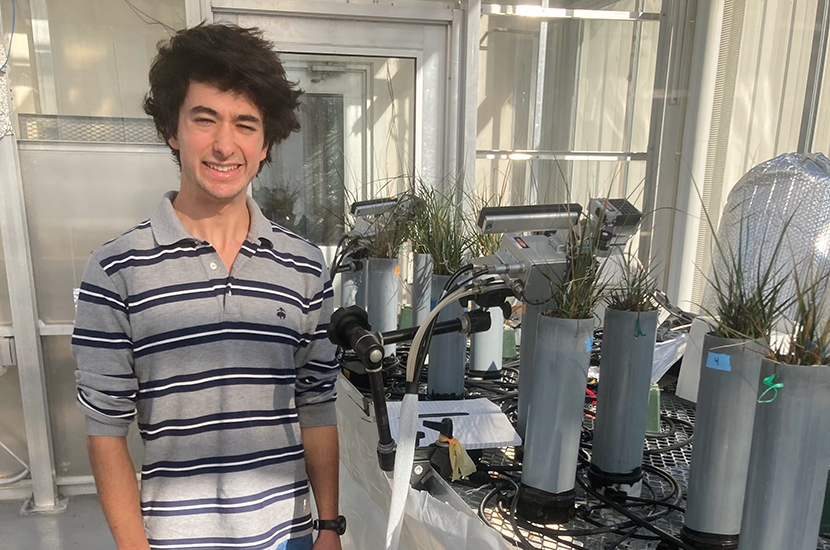 Student in green house with scientific measurement tools.