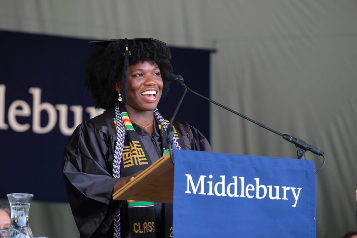 Student in commencement regalia stands at the podium