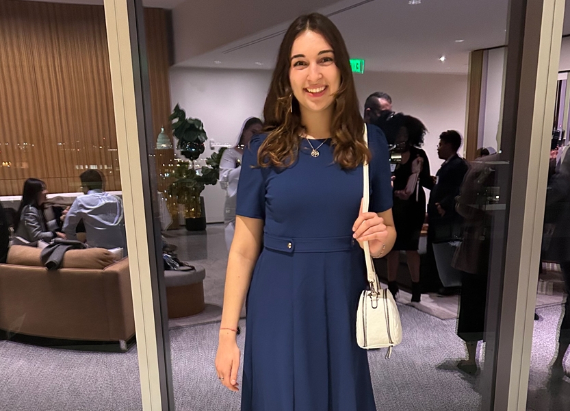 Photo of student standing outside an office, smiling at the camera.