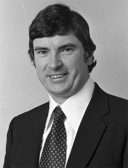 Portrait photo of a man wearing a white shirt, necktie, and blazer.