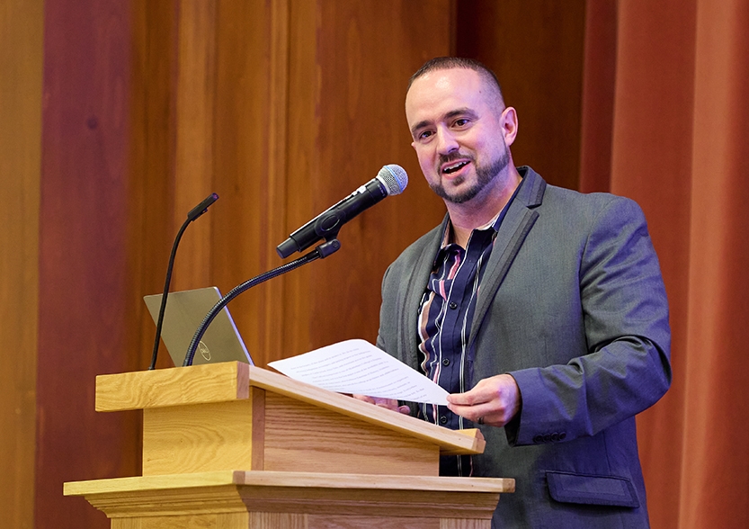 A speaker offers remarks at a lectern on a stage.