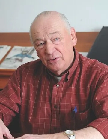 Photo of a man in long-sleeve red shirt sitting at a desk.