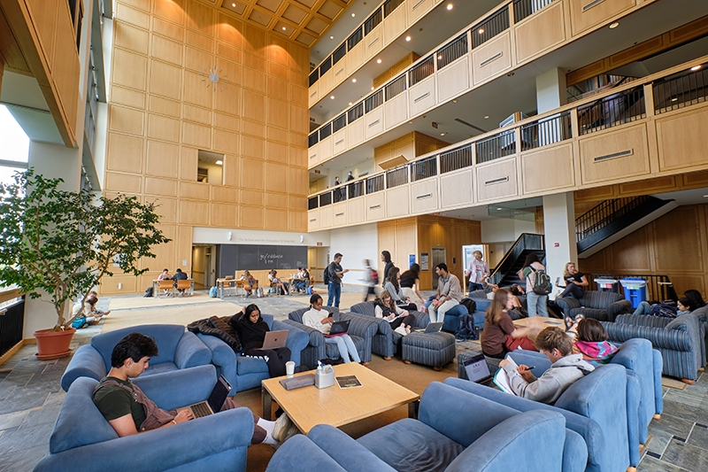 Students sit and study in comfy chairs in the great hall of Bicentennial Hall.