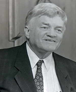 Head shot of man standing at lectern, smiling