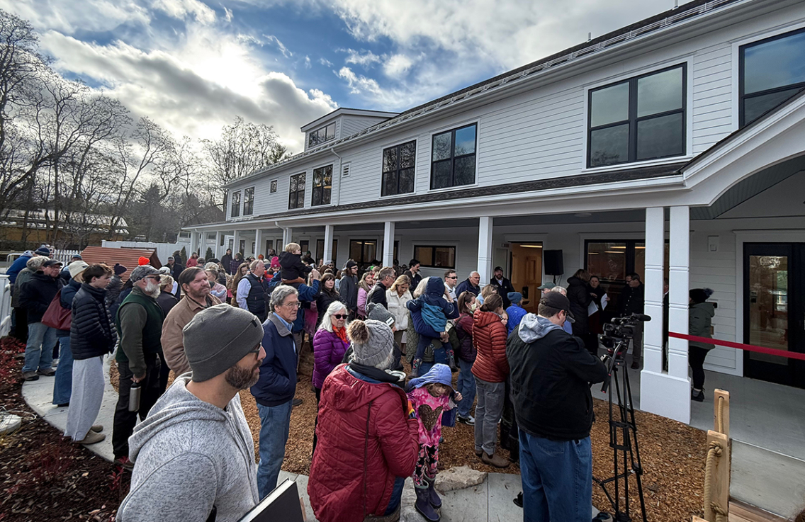 A crowd gathers outside a white building.