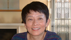 Headshot of woman wearing a dark striped sweater and smiling.