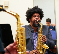 Photo of Professor Matthew Evan Taylor playing saxophone with students.