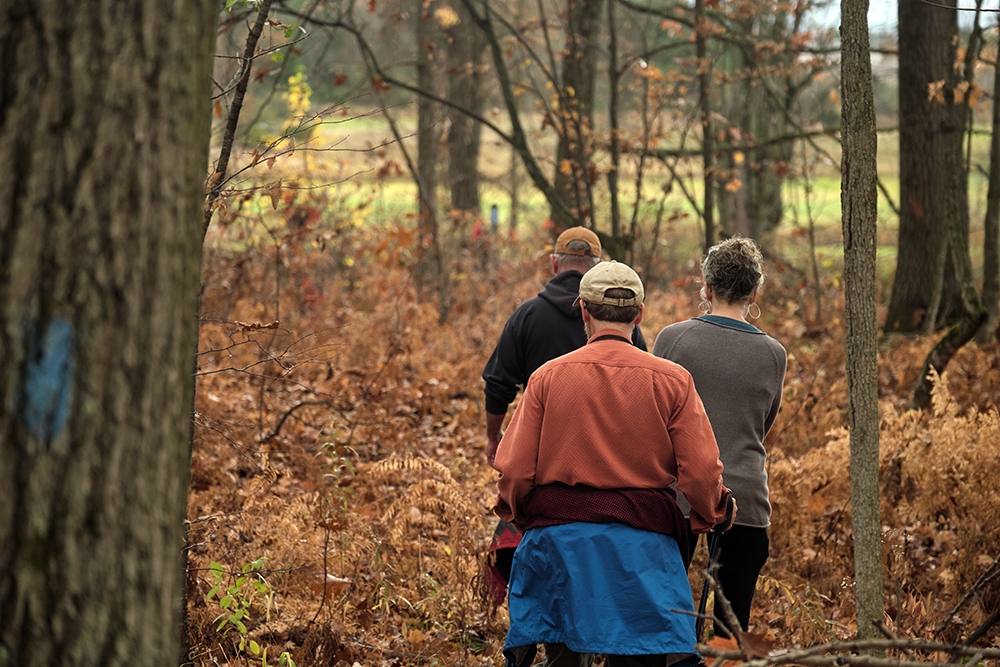 Three people hike through the Trombulak Nature Sanctuary just east of the Middlebury College Campus.