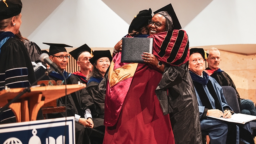 A grad receives her diploma and a hug at LS commencement.