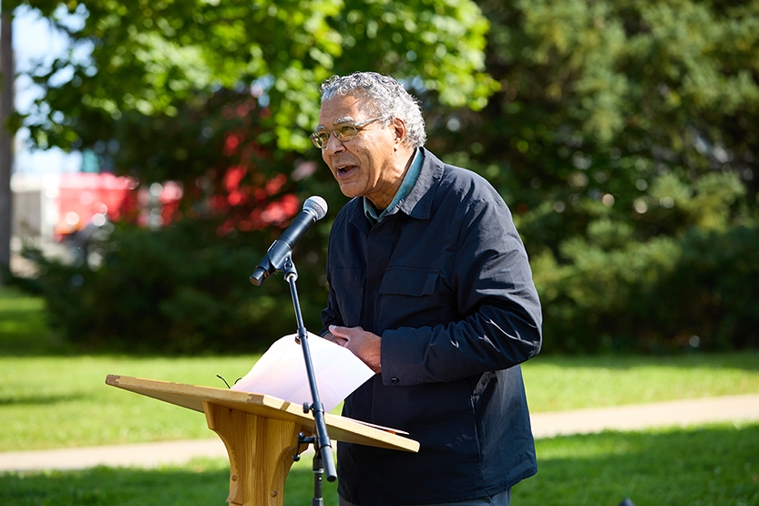 A person speaks at a lectern at an outdoor event.