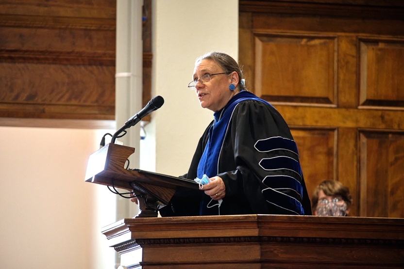 Middlebury president Laurie Patton in academic regalia speaks from the podium in Middlebury chapel.