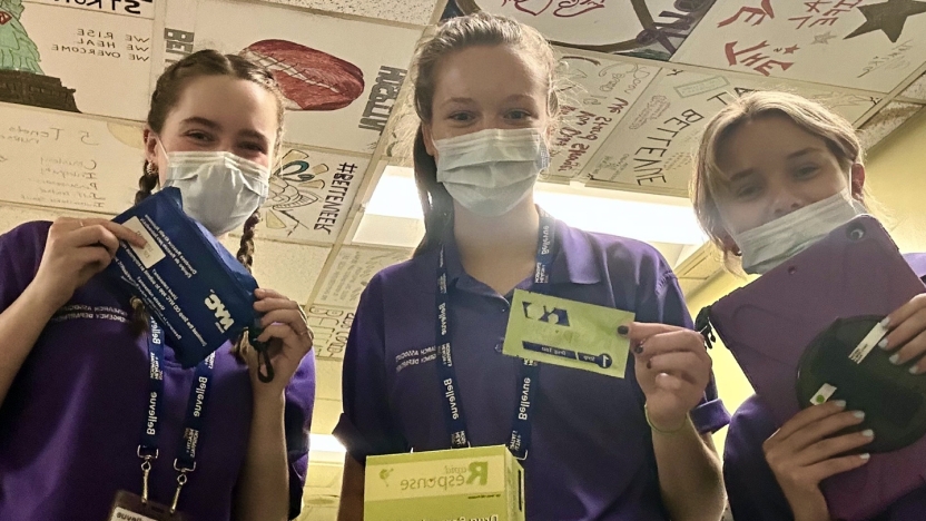 Three college interns wearing medical masks pose for a photo.