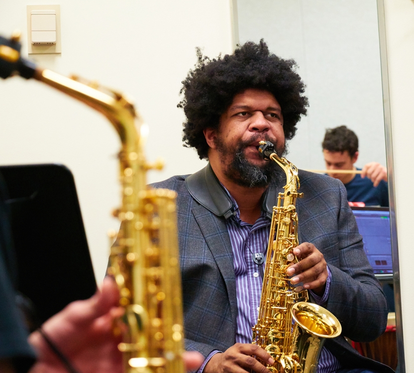 Photo of Professor Matthew Evan Taylor playing saxophone with students.
