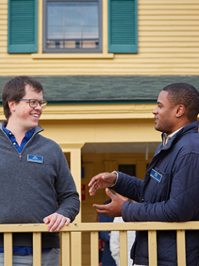 Alumni volunteers Sam Libby and David Ellis smile and chat on the terrace of a Bread Loaf building on a pleasant fall day.