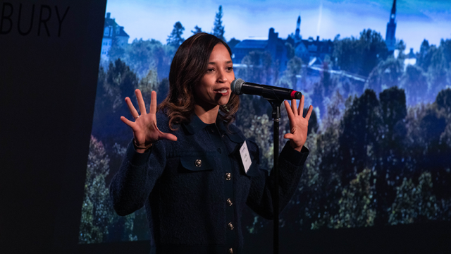 Julisa Salas with raised, open hands as she tells her story in front of a forest backdrop