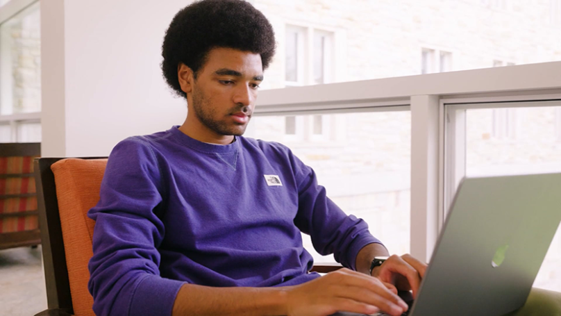 Malick Thiam working at his laptop on a bright day in Axinn