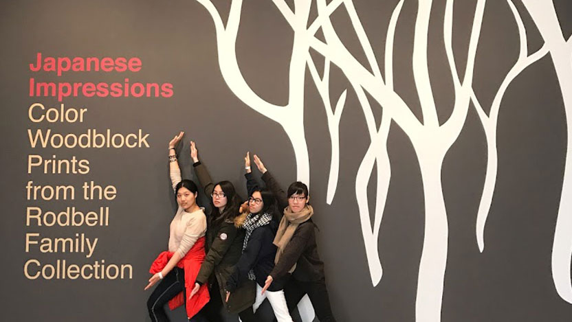 Four students pose in front of a large sign