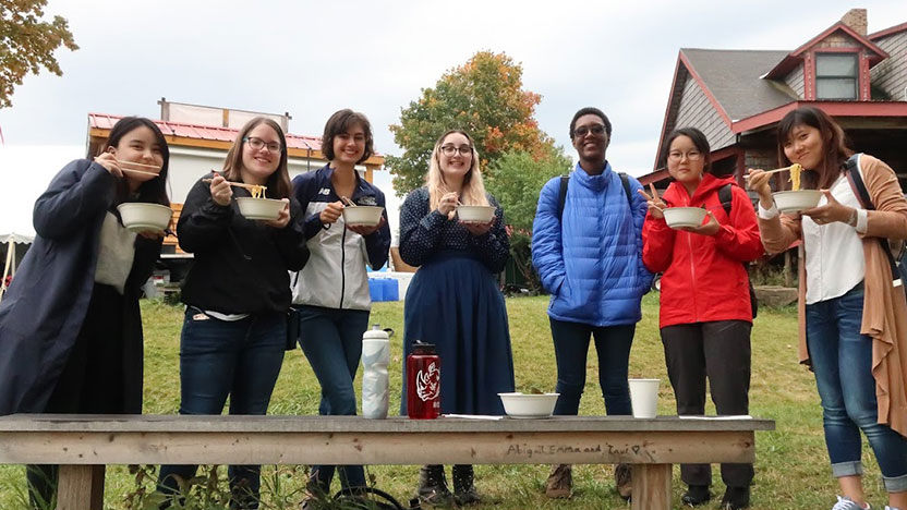 Seven Japanese students eat together outdoors.