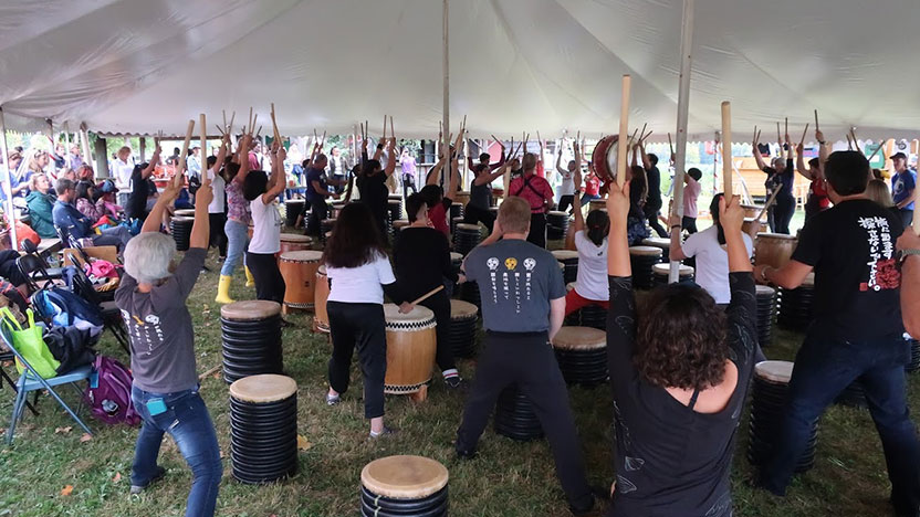 A large group celebrate Japanese culture in an outdoor tent.
