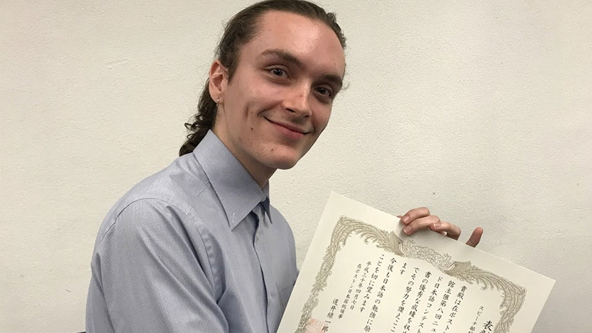 A student holds his winning certificate